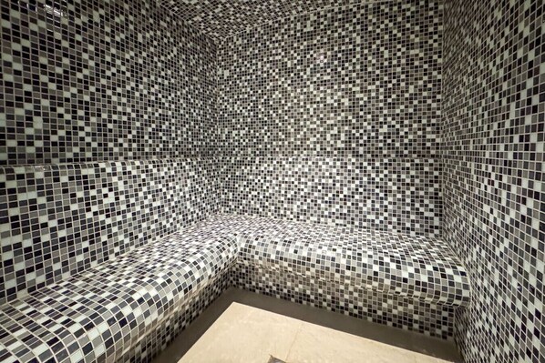 A corner of a room with a checkered mosaic tile floor and walls, creating a patterned design.