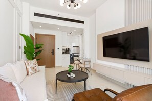 A modern living room with a sofa, a coffee table, a TV, and a kitchen in the background.