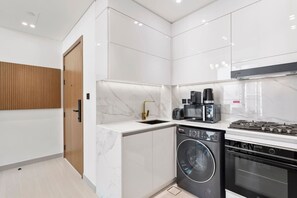 Una cocina moderna con lavadora integrada, horno y cafetera.