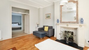 A modern living room with a fireplace, a sofa, and a large mirror. - Charming 1BR Flat in Quiet S Kensington (London)