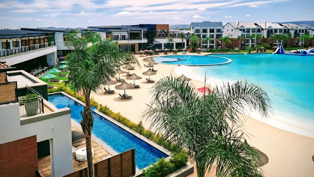 Ein Resort mit mehreren Schwimmbecken, einem Strandbereich und modernen Gebäuden.