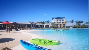 Ein Resort mit großem Pool, Strandbereich und einem Gebäude mit mehreren Balkonen.