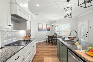 Une cuisine moderne avec des meubles blancs, un plan de travail en granit et un coin repas comprenant une table et des chaises.