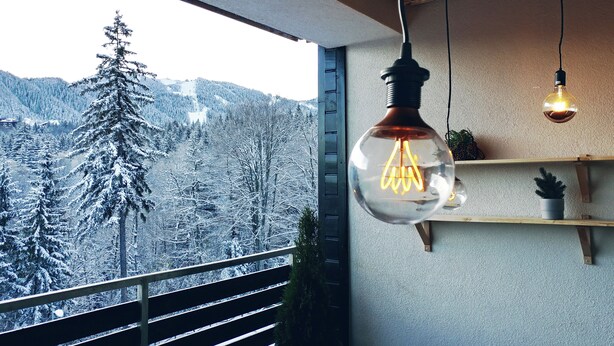 A balcony with a view of snow-covered trees and mountains.