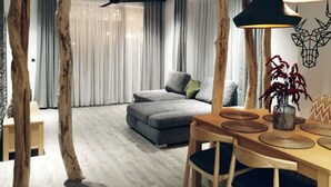A modern living room with a grey sofa, wooden dining table with woven placemats, and a ceiling fan.