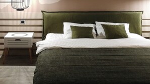 A bedroom with a bed, a nightstand, a hanging light fixture, and a wall with a mountain mural.