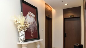 A hallway with a framed artwork of a bird, a white vase with dried flowers, and a door labeled 208. - Arjan Park Al Qadisiyah (Riyadh)
