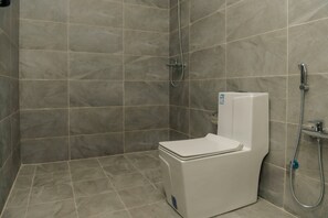 Un bagno con doccia, servizi igienici e un pannello di controllo a parete.
