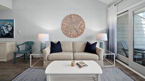 A living room with a striped sofa, two side tables with lamps, a coffee table, a large circular wall art piece, and a painting on the wall.