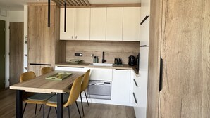 A modern kitchen with white cabinets, a wooden countertop, and a built-in dishwasher. - Stunning renovated T2, air conditioning, parking, balcony - City and mountain views (Aix-les-Bains)