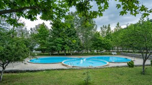 A swimming pool surrounded by trees and a stone wall. - Qabala Semerena Riverside Hotel (Gabala)