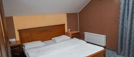 Un dormitorio con cama de madera, mesita de noche, cómoda, equipo de aire acondicionado y alfombra estampada.