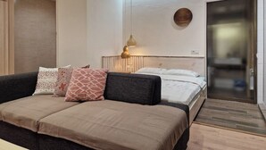 A modern hotel room with a sofa, two beds, a wall clock, a pendant light, and a sliding door. - Cozy apartment in the city center with AC & Wi-Fi (Tashkent)