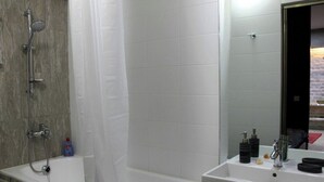 A modern bathroom with a bathtub, shower, and sink. - Cozy apartment in the city center with AC & Wi-Fi (Tashkent)