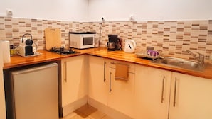 A compact kitchen with a microwave, coffee maker, and a small sink. - Quiet studio for two, wheelchair accessible, near golf and beaches (Les Avirons)