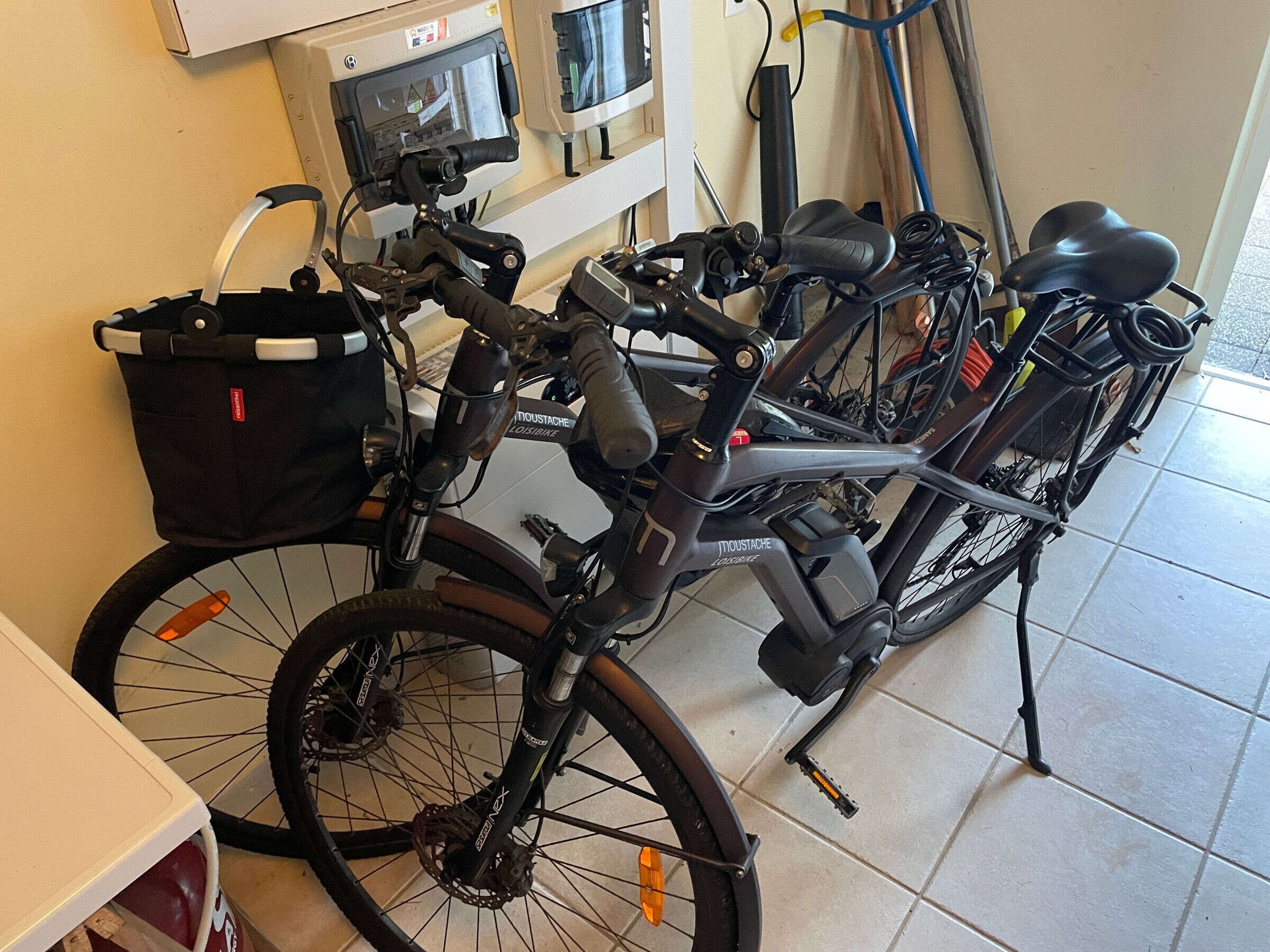 A bicycle with a basket and a water bottle attached, parked indoors.