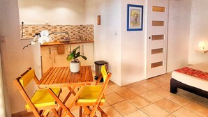 A compact living space with a dining area, kitchenette, and a bed. - Quiet studio for two, wheelchair accessible, near golf and beaches (Les Avirons)