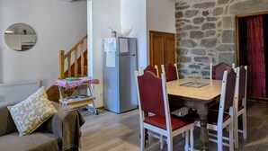 A compact living space with a dining area, a refrigerator, a wooden staircase, and a stone wall. - Rustic stay near Estables and Puy-en-Velay (Saint-Front)