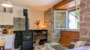 A cozy room with a stone wall, a wooden ceiling, a fireplace, a sofa, and a dining area with a table and chairs. - Rustic stay near Estables and Puy-en-Velay (Saint-Front)