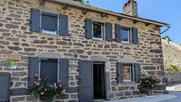 A stone building with multiple windows and shutters, a sign indicating a restaurant, and flowers in the window boxes. - Rustic stay near Estables and Puy-en-Velay (Saint-Front)