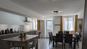 A modern kitchen with a dining area, a large window, and a door.