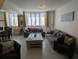 A living room with a sofa, a coffee table, a dining table with chairs, and a lamp.