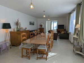 Ruokailutila, jossa on puinen pöytä ja tuolit, televisio ja sohva.