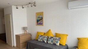 Une chambre à coucher avec un lit, une table de chevet, une lampe et un petit tabouret.