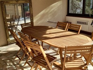 A sunlit patio with a wooden table and chairs, a large mirror, and a window with a view of greenery. - Spacious Family Home with Pool and Parking in Saint-Gaultier (Saint-Gaultier)