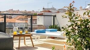 Terraza en la azotea con mesa, sillas, una planta en maceta y vista panorámica de la ciudad.