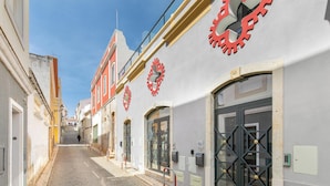 Una calle adoquinada con edificios que tienen ventanas grandes y decoraciones rojas con forma de engranaje.