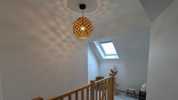 A staircase with a wooden railing leading to a room with a skylight.