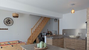 A modern kitchen with wooden cabinets, a built-in stove, and a dining area with a foosball table.