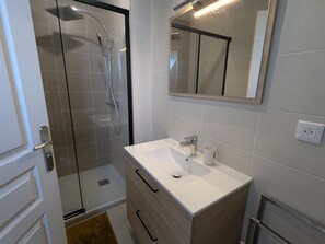 Ein Badezimmer mit Duschkabine, Waschbecken mit Spiegel und Toilette.
