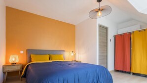 Une chambre avec un grand lit, deux lampes de chevet et un ventilateur de plafond.