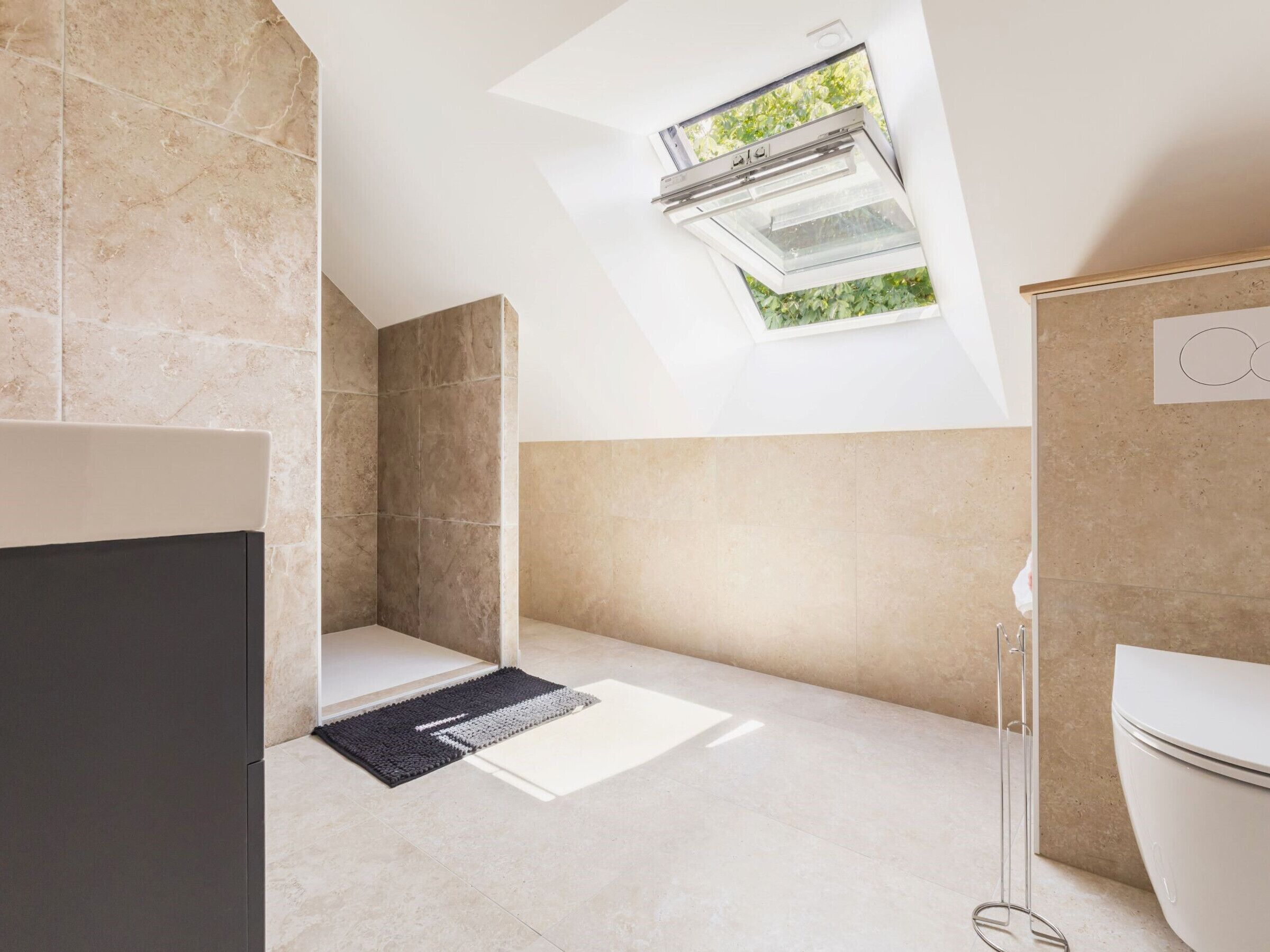 A modern bathroom with a skylight, a shower, and a toilet.