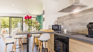Une cuisine moderne dotée d’un îlot central, de tabourets de bar, d’un four à micro-ondes, d’une machine à café et offrant une vue sur l’extérieur.