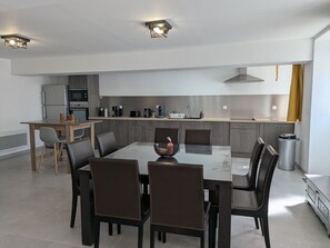 A modern kitchen with a dining area, featuring a wooden table, chairs, and built-in appliances.