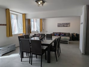 Un espacio moderno con comedor, juegos de sofá y un cuadro de la ciudad.