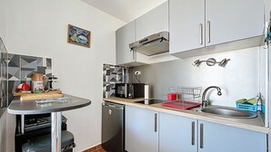 A compact kitchen with grey cabinets, a microwave, a coffee maker, and a dish rack. - Bright studio 4 pers, near beach with Wi-Fi (Mauguio)