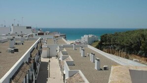 Eine Dachterrasse mit Meerblick, Klimaanlagen und einem wolkenlosen Himmel.