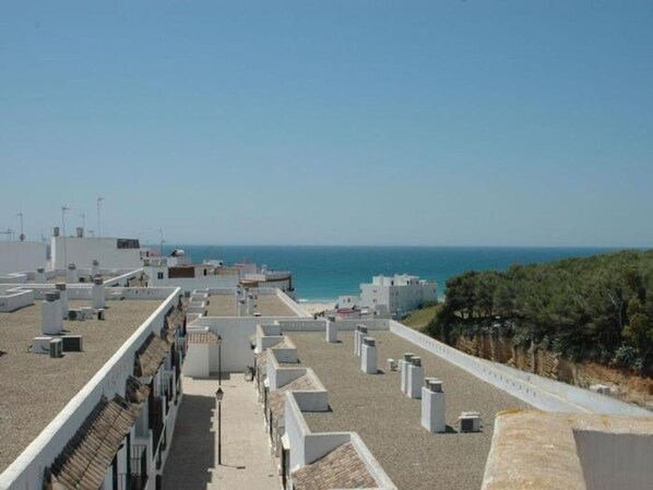 A rooftop terrace with a view of the sea, air conditioning units, and a clear sky.