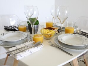 A dining table set with plates, cutlery, glasses, and a bowl of chips.