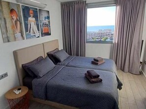 A hotel room with a bed, a small table, and a window with curtains. - New luxury complex near the sea (Playa Paraiso)