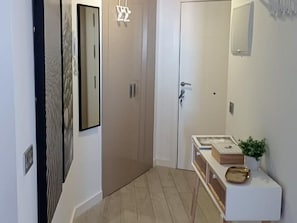 A hallway with a door, a mirror, and a small table with a plant and a tray.