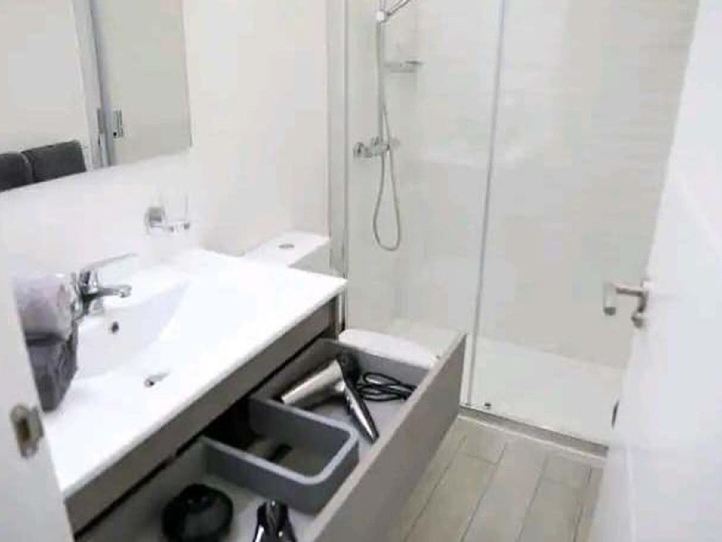 A modern bathroom with a white sink, mirror, and shower.