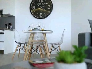 A modern dining area with a round table, clear chairs, and a wall clock. - New luxury complex near the sea (Playa Paraiso)