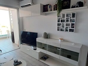 A modern living room with a flat-screen TV, a white entertainment unit, and a wall-mounted photo collage. - New luxury complex near the sea (Playa Paraiso)