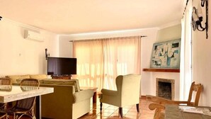 Un salon avec un canapé, des fauteuils, un téléviseur et une cheminée.