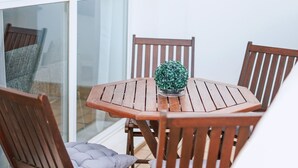 A wooden table with four chairs, a small potted plant, and a cushion on one chair.
